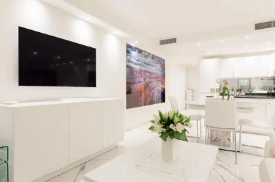 a white living room with a large flat screen tv at On La Croisette: new 2 bedrooms with sea view in Cannes