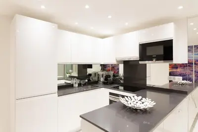 a kitchen with white cabinets and a black counter top at On La Croisette: new 2 bedrooms with sea view in Cannes