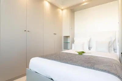a bedroom with a large bed with white walls at On La Croisette: new 2 bedrooms with sea view in Cannes