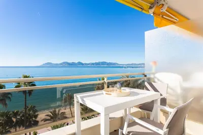 a white table and chairs on a balcony overlooking the ocean at On la Croisette: luxe 2 bedrooms/ 2 baths in Cannes