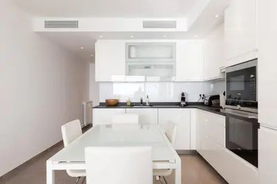 a white kitchen with a white table and chairs at On la Croisette: luxe 2 bedrooms/ 2 baths in Cannes