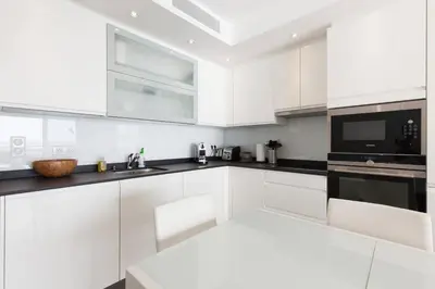 a white kitchen with white cabinets and black counter tops at On la Croisette: luxe 2 bedrooms/ 2 baths in Cannes