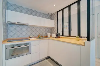 a kitchen with white cabinets and a large window at IMMOGROOM - AC - 5min from the beaches 8 min from Palais in Cannes