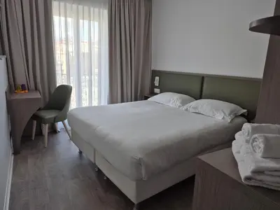 a hotel room with a large bed and a window at Hôtel Ligure in Cannes