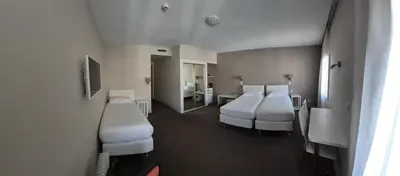 a hotel room with two beds and a bathroom at Hôtel Ligure in Cannes