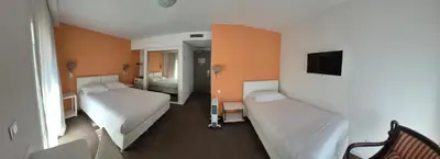 a hotel room with two beds and a tv at Hôtel Ligure in Cannes