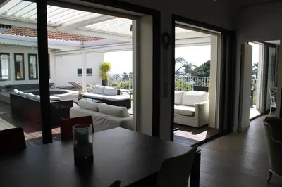 a dining room with a table and a living room at Rooftop grande terrasse jacuzzi vue mer in Cannes