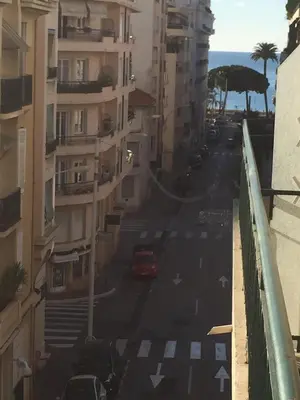 a red car driving down a city street with buildings at PASTEUR in Cannes