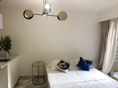 a bedroom with a bed with white sheets and blue pillows at Studio contemporain à Cannes avec terrasse et parking - 35 m² in Cannes
