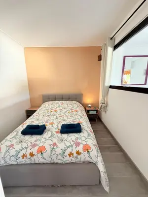 a bedroom with a bed with two blue pillows on it at Le Gallieni in Cannes