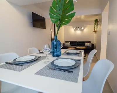 a dining table with white chairs and a vase with a plant at Appartement centre de Cannes in Cannes
