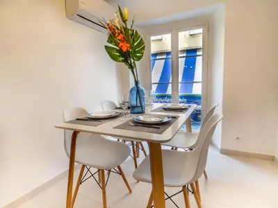 a dining room table with chairs and a vase with flowers at Appartement centre de Cannes in Cannes