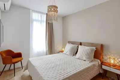 a white bedroom with a bed and a chair at Luxe et Confort - Proche Palais et plages - A/C in Cannes