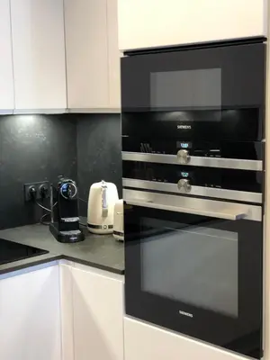 a black oven in a kitchen with white cabinets at Luxe et Confort - Proche Palais et plages - A/C in Cannes