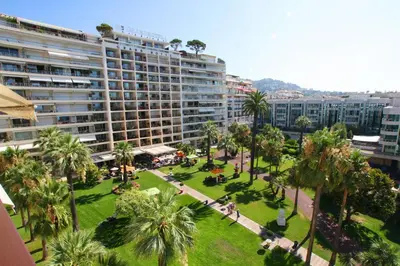 a park with palm trees and a large building at STUDIO 45 CROISETTE CANNES in Cannes