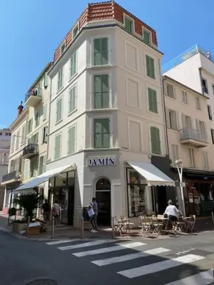a tall white building with tables and chairs on a street at Scandinavian Urban 4 - 1BR apartment in Cannes center close to the beach and the Palais in Cannes