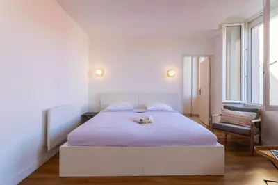 a white bedroom with a bed and a chair at Marechal Foch / GOLD2025 / ST in Cannes