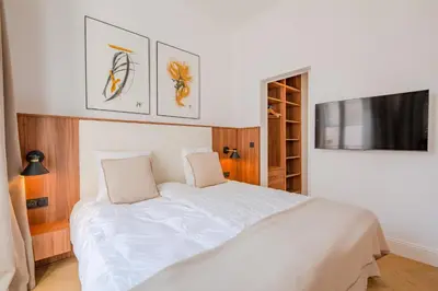 a bedroom with a white bed and a flat screen tv at La Guitare 21 - Cozy studio in center of Cannes, just behind Grand Hotel in Cannes
