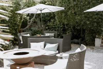 a patio with a table and chairs with an umbrella at Ideal Sejour Cannes - Hôtel de Charme in Cannes