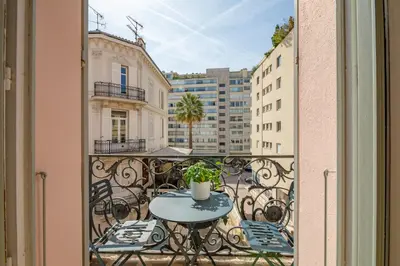 a balcony with a table and chairs and buildings at La Guitare 22 - Spacious 1 BR apartment in the center of Cannes, right behind Grand Hotel in Cannes