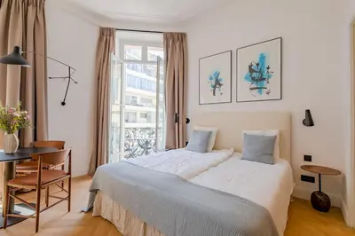 a bedroom with a bed and a table and a window at La Guitare 23 - Large modern studio with balcony in center of Cannes, just behind Grand Hotel in Cannes