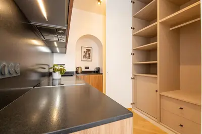 a kitchen with a black counter top and shelves at La Guitare 23 - Large modern studio with balcony in center of Cannes, just behind Grand Hotel in Cannes