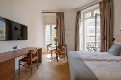 a bedroom with a bed and a desk and a table at La Guitare 23 - Large modern studio with balcony in center of Cannes, just behind Grand Hotel in Cannes