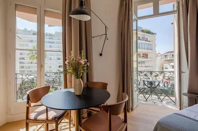 a room with a table and chairs and a balcony at La Guitare 23 - Large modern studio with balcony in center of Cannes, just behind Grand Hotel in Cannes