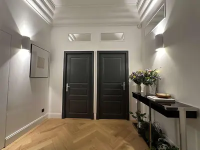 a hallway with two black doors and a vase of flowers at La Guitare 24 - Nice studio in center of Cannes, just behind Grand Hotel in Cannes