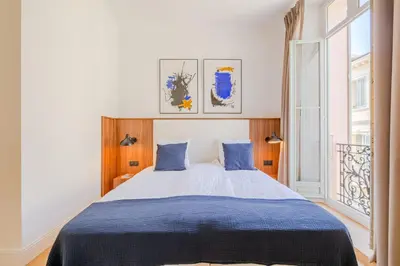 a bedroom with a bed with blue sheets and a window at La Guitare 24 - Nice studio in center of Cannes, just behind Grand Hotel in Cannes