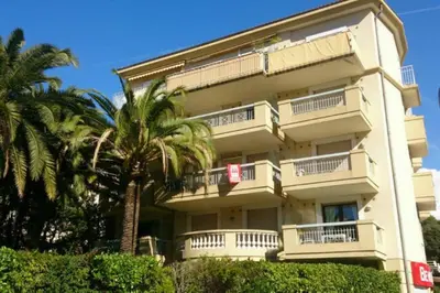 a tall white building with palm trees in front of it at Cannes près Croisette beau 2 pièces 3 étoiles in Cannes