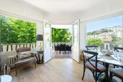 a living room with a table and chairs and a balcony at Cozy 2-Br Apartment 6 Minutes from the Beach in Cannes