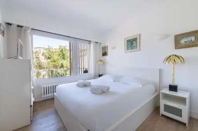 a bedroom with a white bed and a large window at Cozy 2-Br Apartment 6 Minutes from the Beach in Cannes