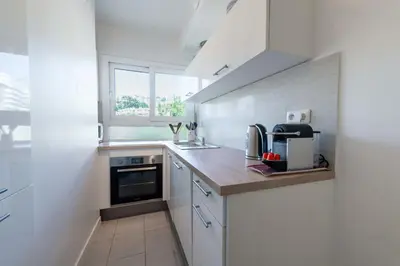a kitchen with white cabinets and a sink and a window at Cozy 2-Br Apartment 6 Minutes from the Beach in Cannes