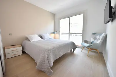 a bedroom with a bed and a chair and a window at 3-Room Apartment in the Heart of Cannes in Cannes