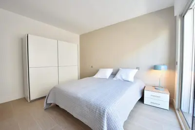 a white bedroom with a bed and a dresser at 3-Room Apartment in the Heart of Cannes in Cannes