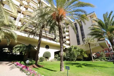 a hotel with palm trees in front of a building at Luxury 1 bedroom Jardins Croisette 5 mins Croisette 265 in Cannes