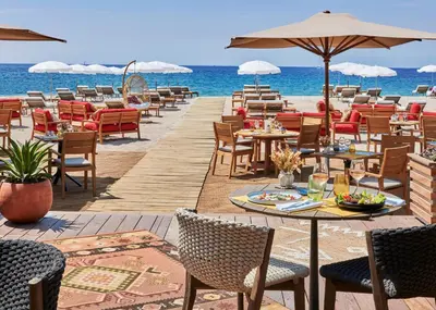 a restaurant on the beach with tables and chairs at Hôtel Barrière Le Gray d'Albion in Cannes
