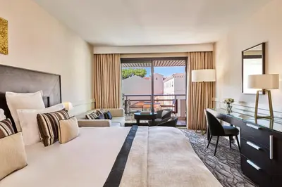 a hotel room with a bed and a balcony at Hôtel Barrière Le Gray d'Albion in Cannes