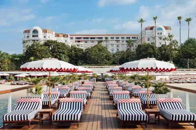 a row of chairs with umbrellas in front of a hotel at Hôtel Barrière Le Majestic Cannes in Cannes