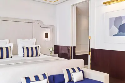 a bedroom with a large bed with blue and white pillows at Hôtel Barrière Le Majestic Cannes in Cannes