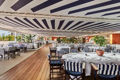 a dining room with tables and chairs and a striped ceiling at Hôtel Barrière Le Majestic Cannes in Cannes