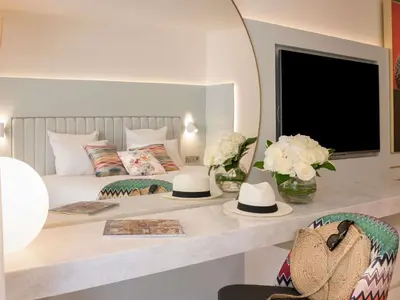 a bedroom with a bed with a table with hats on it at Croisette Beach Hotel Cannes - MGallery Collection in Cannes