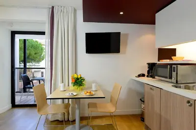 a kitchen with a table with chairs and a microwave at Résidence Residéal Premium Cannes in Cannes