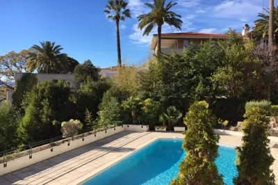 a swimming pool in a yard with palm trees at Stunning 3-Br Apartment with Large Terrace and Pool in Cannes