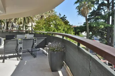 a balcony with a table and chairs and palm trees at CANNES - 2-BR flat 15-min walk to the beaches in Cannes