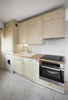 a kitchen with wooden cabinets and a stove and a sink at Cannes Croisette Prestige Apart'hotel in Cannes