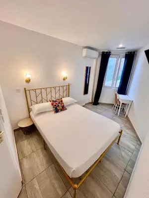 a bedroom with a bed and a table and a window at Appia Hotel in Cannes