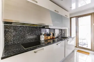 a kitchen with white cabinets and a black counter top at Agence AICI - Appartements Gray d'Albion in Cannes