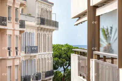 a large building with palm trees in front of it at Agence AICI - Appartements Gray d'Albion in Cannes